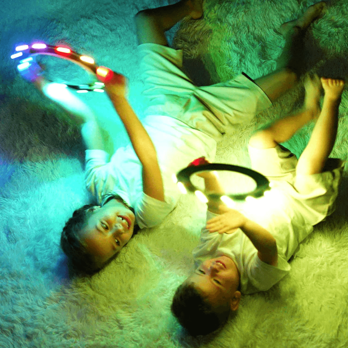 Two children playing with TOSY Flying Rings on a fluffy white carpet