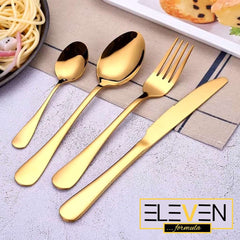 Close-up of Eleven Formula 16 Piece Gold Stainless Steel Silverware Set beside plated food, featuring brand logo and polished finish.
