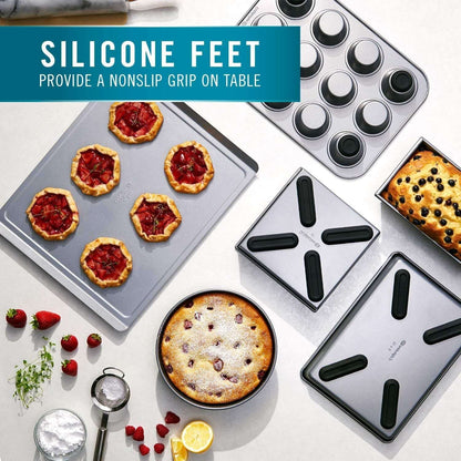Calphalon 6 Piece Nonstick Bakeware Set Steel Baking Pans with silicone feet for nonslip grip, displayed with baked goods on a kitchen table.