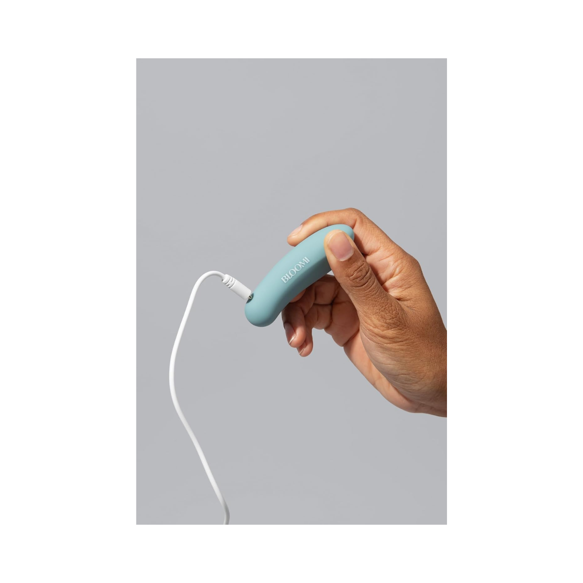 Bloomi Play Waterproof Rechargeable Mini Vibrator being charged via USB cable, emphasizing its rechargeable feature and modern wellness design.