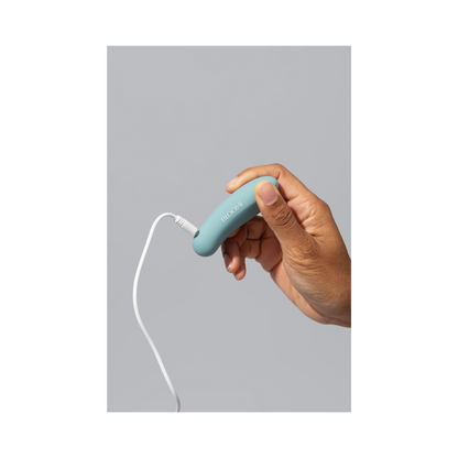 Bloomi Play Waterproof Rechargeable Mini Vibrator being charged via USB cable, emphasizing its rechargeable feature and modern wellness design.