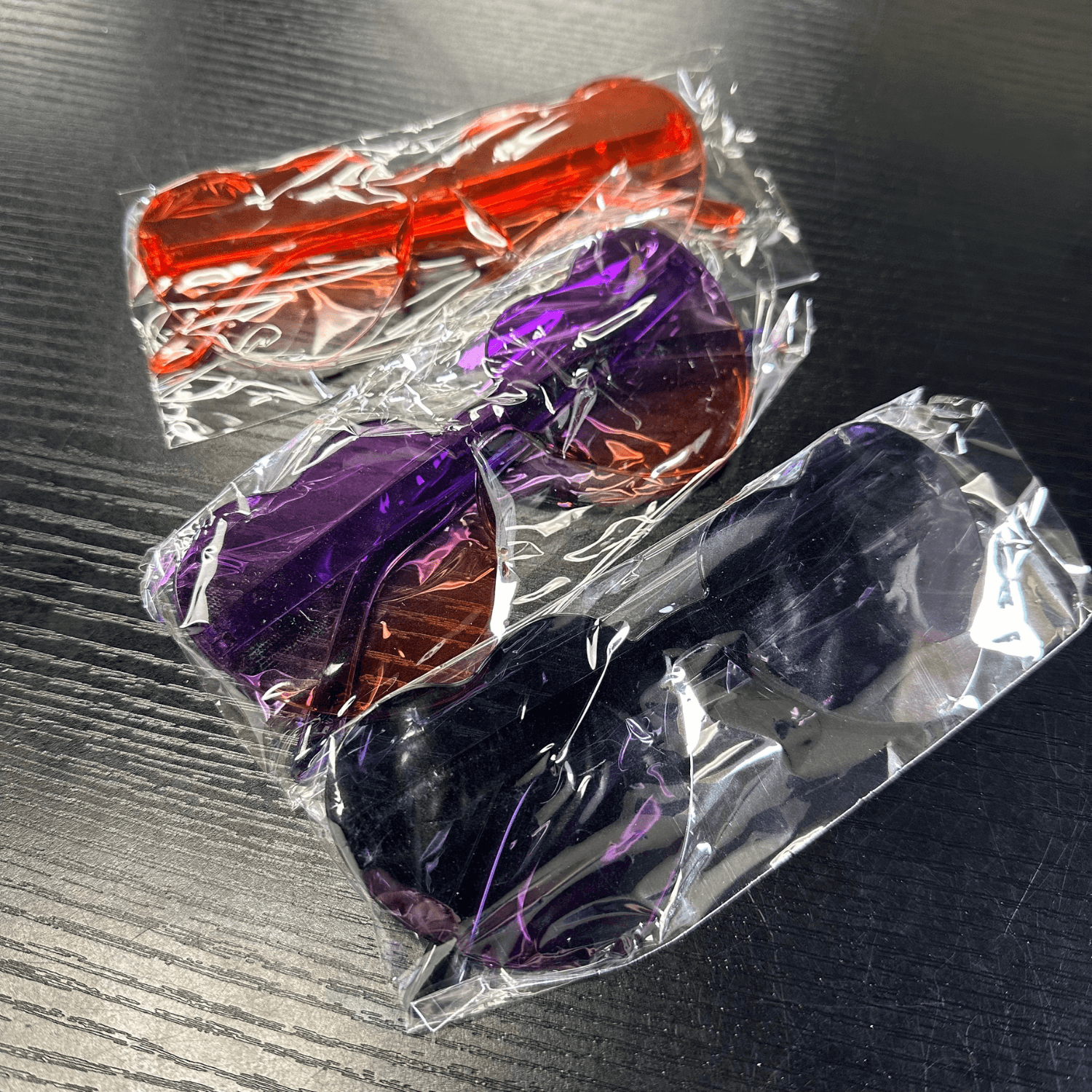 Individually wrapped Kids Heart Sunglasses in orange, purple, and black gradient colors, ideal for party favors or goodie bags.
