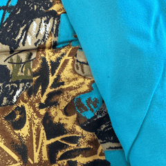 Close-up of The Woods Seabreeze Twin Sheet Set fabric showing detailed nature print and solid turquoise material side by side.