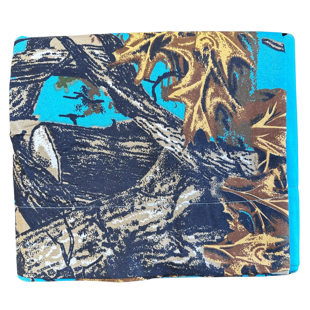 Folded The Woods Seabreeze Twin Sheet Set featuring a vibrant nature print with tree branches and autumn leaves on turquoise background.