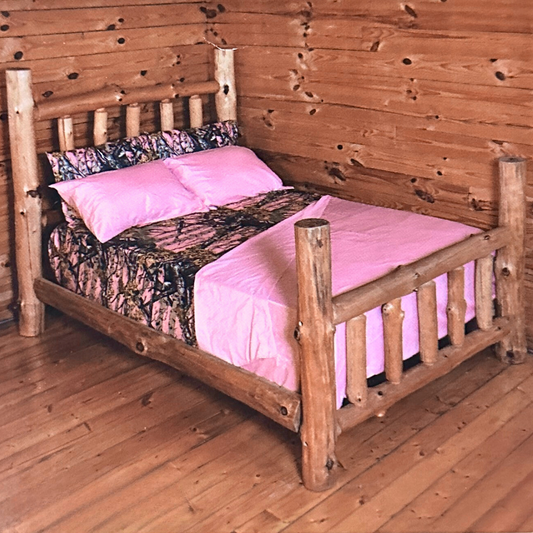 Full Size Pink Camouflage 6 Piece Microfiber Sheet Set on rustic log bed, featuring pink and camo patterns for a cozy cabin-style bedroom decor.
