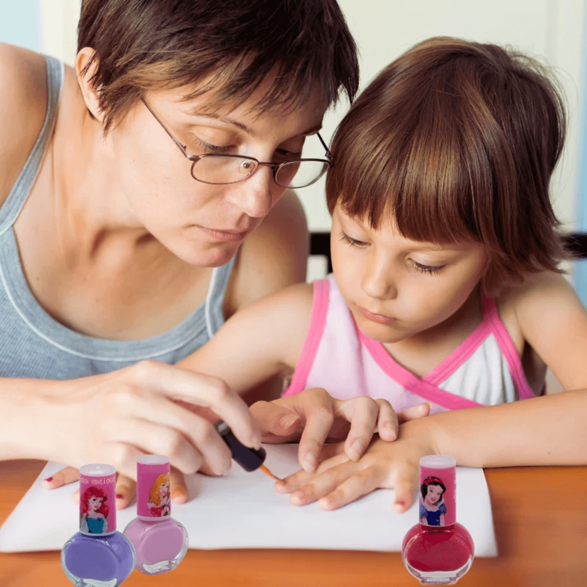 Adult helping child apply Disney Princess washable nail polish. Fun, safe nail care activity using non-toxic kids' polish set.