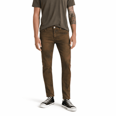 Model wearing brown AG jeans. White background.