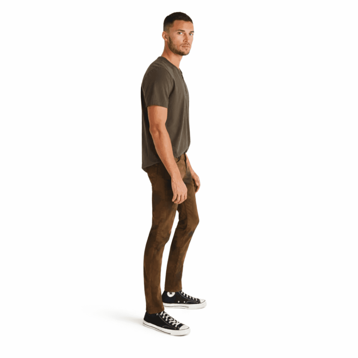 Man wearing a green t-shirt and brown AG jeans on a white background