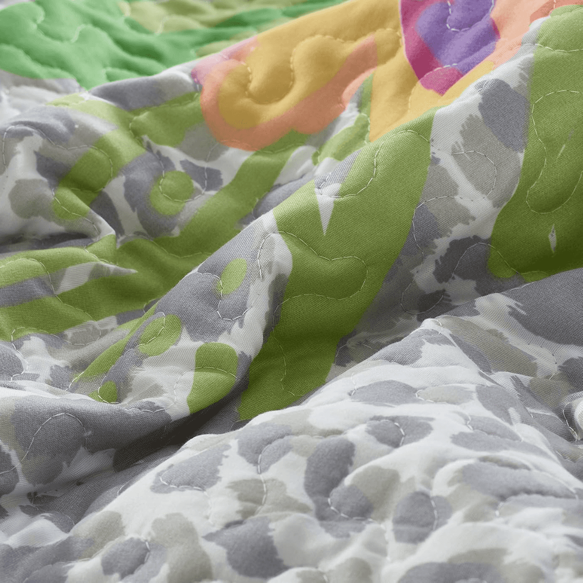 Close-up of a colorful quilt with green, gray, and multicolor patterns.