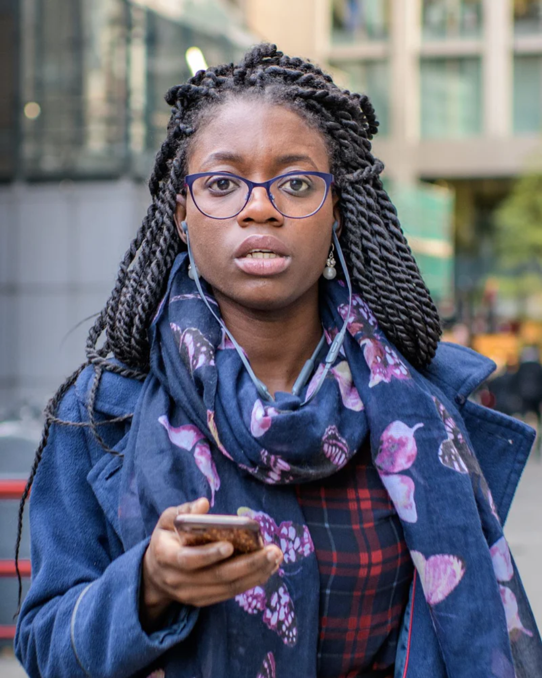 Black woman holding cellphone and looking at the camera
