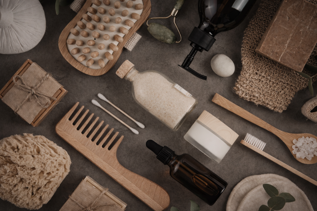 Collection of natural beauty products including a bottle, brush, and soap on a textured surface.