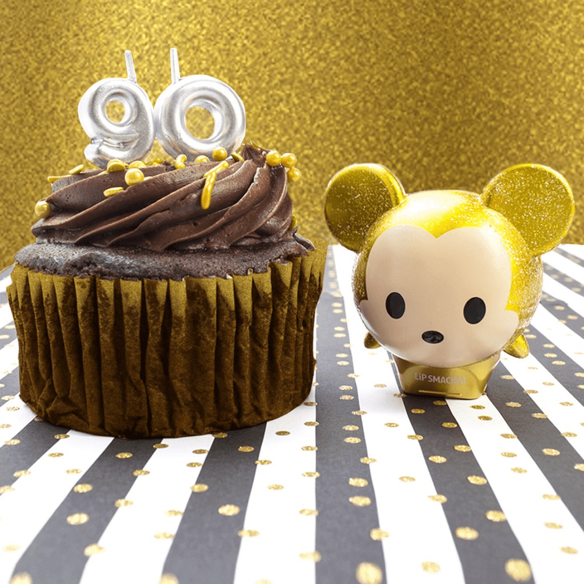 Disney Mickey Minnie lip balm duo with gold glitter design and character toppers, alongside a cupcake