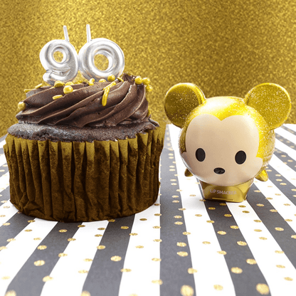 Disney Mickey Minnie lip balm duo with gold glitter design and character toppers, alongside a cupcake