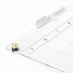 Close-up of dry erase marker and transparent acrylic calendar with gold accents for office supplies