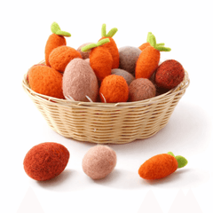Wicker basket filled with felted carrot toys on a white background