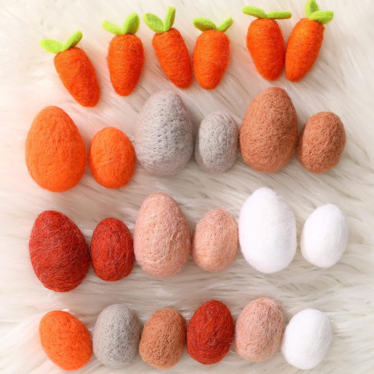 Set of felt carrots and eggs on a light wooden surface