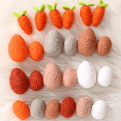 Set of felt carrots and eggs on a light wooden surface