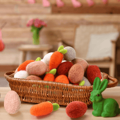 Wicker basket filled with felted wool carrots and eggs on a wooden surface.