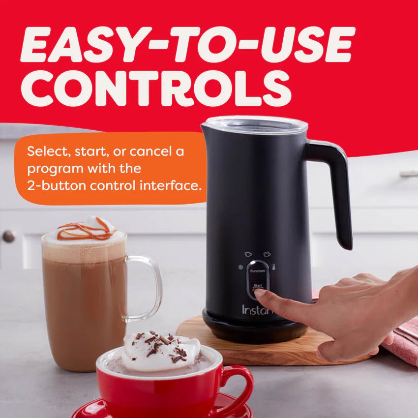 Black milk frother with a hand pressing a button, surrounded by hot beverages on a kitchen counter.