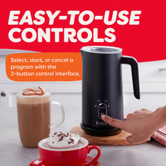 Black milk frother with a hand pressing a button, surrounded by hot beverages on a kitchen counter.