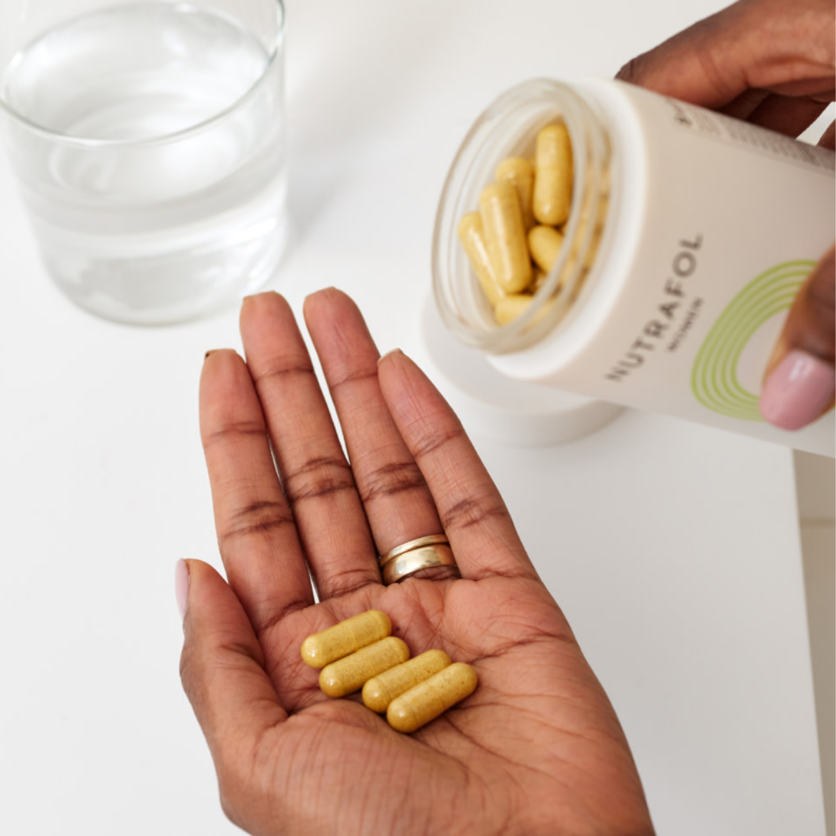 Woman about to take a Nutrafol capsule