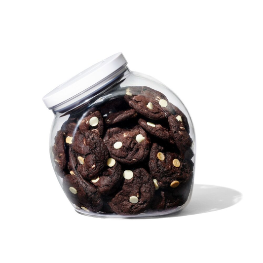 A glass food storage jar with white lid and cookies inside
