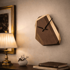 Wooden wall clock on a wall with a lamp and books in the foreground