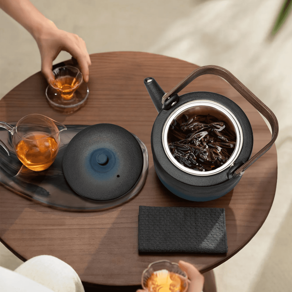 Tea-making setup with a teapot, cups, and a wooden table.