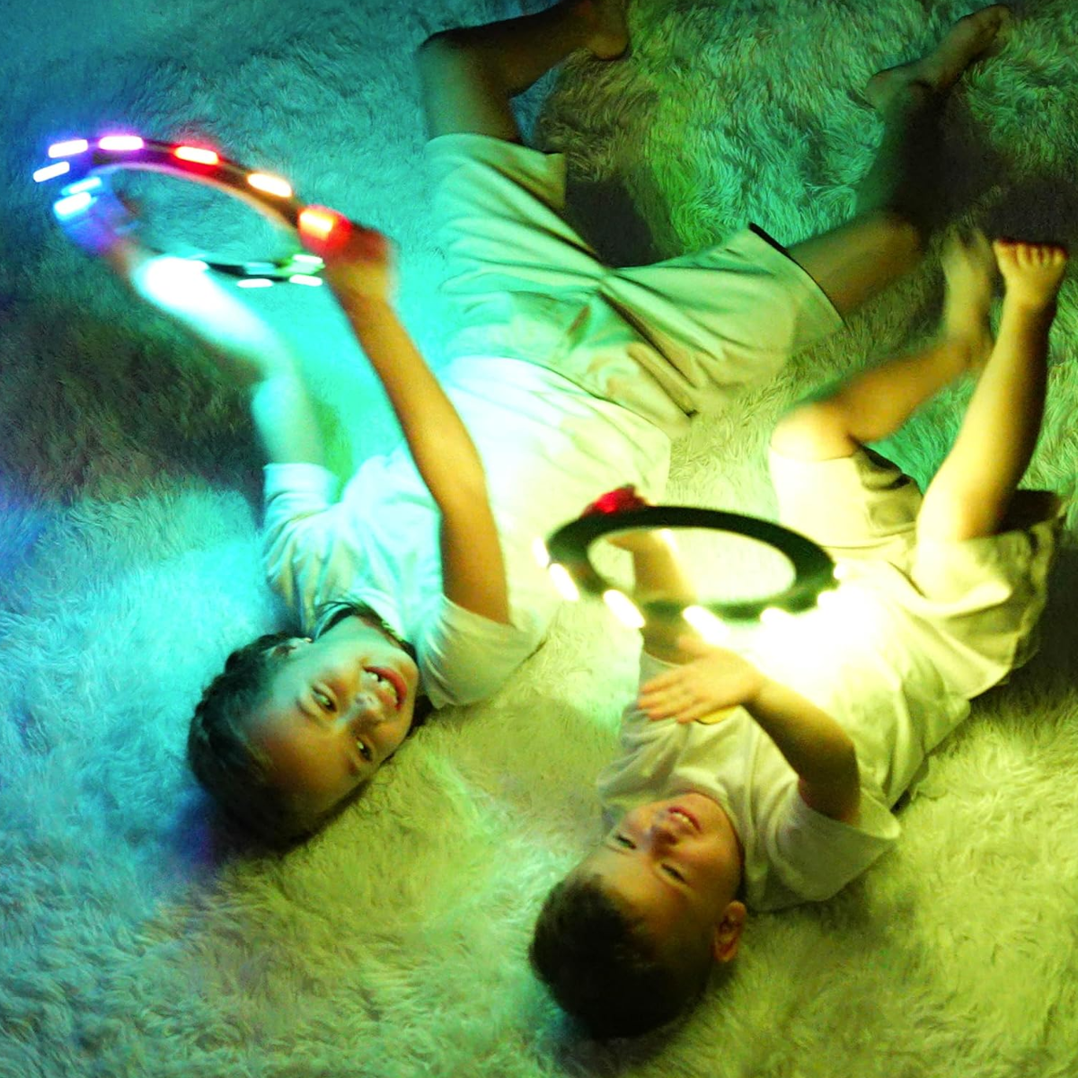 Two children playing with TOSY Flying Rings on a fluffy white carpet