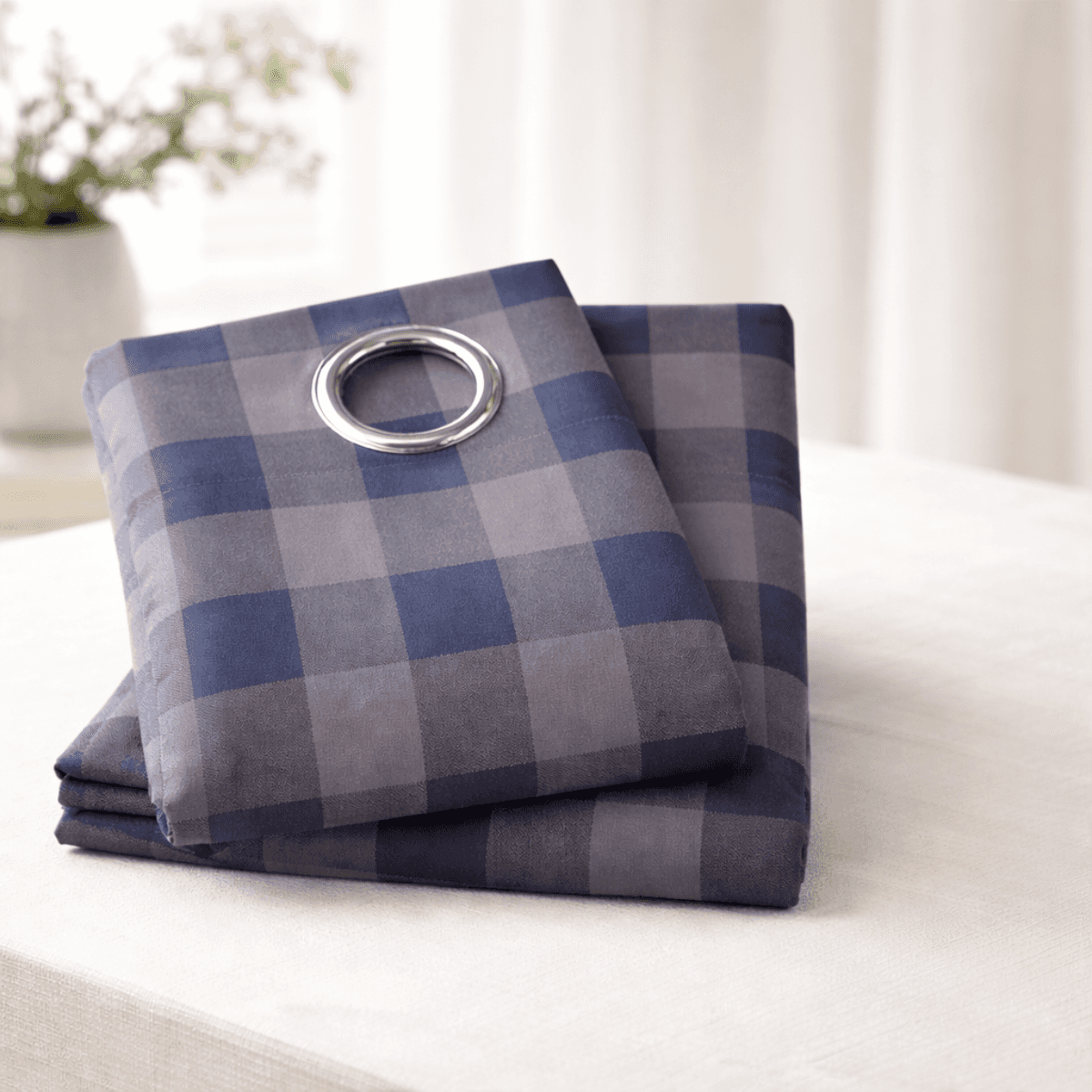 Folded blue and gray checkered curtain set on a white surface
